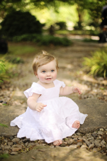 A small girl wearing a white dress playing