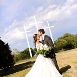 Bride and Groom holding white flowers together on a field