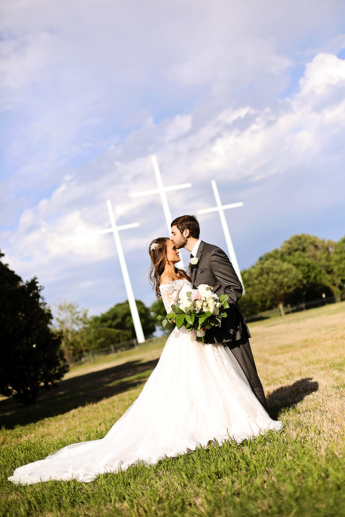 Bride and Groom holding white flowers together on a field