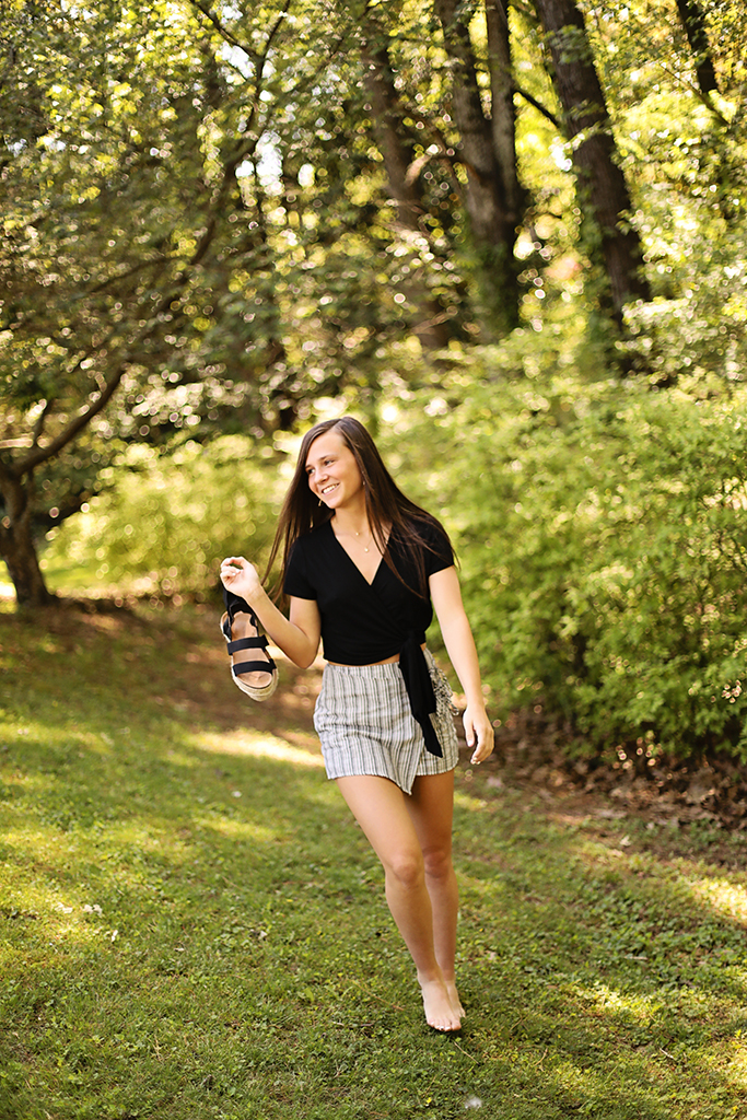 A girl in the woods walking barefoot and smiling