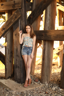 A lady posing in front of a wooden structure