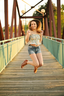 A girl jumping on a wooden bridge