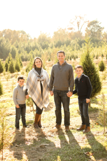 A family of standing with Christmas trees around