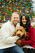 A couple holding their dog with lights behind