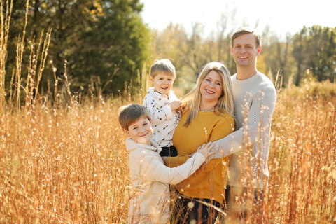 A family of four standing with tall grasses