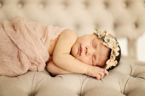 A newborn baby wearing a flower crown