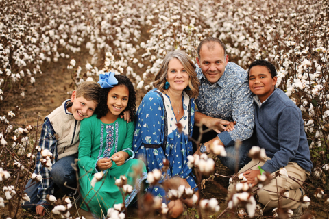 A family of five sitting on the cotton plant field
