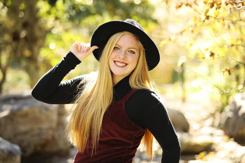 A girl standing wearing a hat and smiling