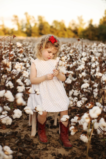 A small girl wearing white in a cotton plant field