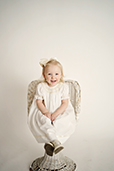 A small girl in white dress sitting on a chair