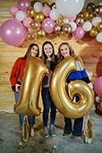 Three girls holding the sign of sixteen
