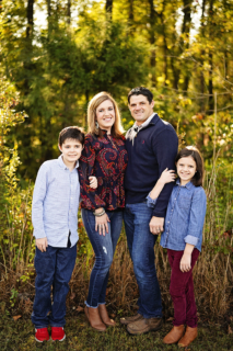 A family of four standing with trees in the background