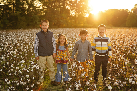 Four children standing with Cotton plants around them
