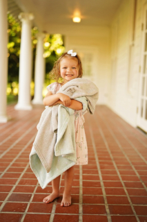 A small girl standing holding towels in hand