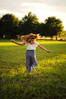 A girl running on grass with trees in background