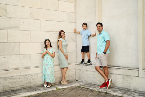 A family of four posing in front of wall