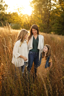 A family of three standing around tall grass