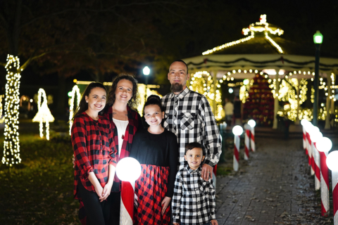 A family of five standing with Christmas decoration all around