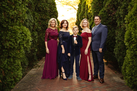 A family of five posing with trees on both side