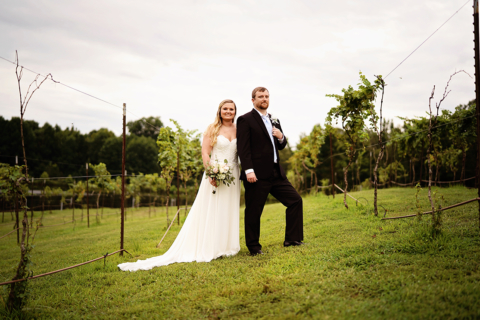 A bride and groom holding white flowers on a field