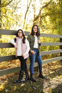 two girls standing near a wooden fence