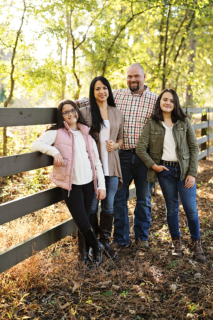 A family of four in front of a wooden fence