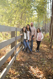 A family of four standing near a wooden fence