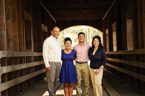 A family of four standing on a wood bridge