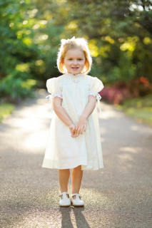 A child wearing white dress and standing on road