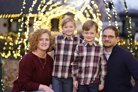 A family of four posing in front of lights