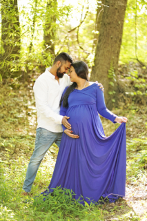 A pregnant woman wearing blue dress with her husband