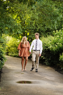 A man and a woman walking of a path with trees all around