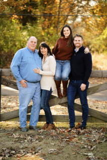 A family of four posing on wooden fence