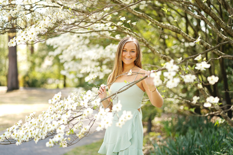 A girl holding a branch of a tree with white flowers