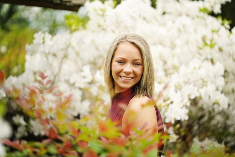 A woman smiling with white flowers in the background