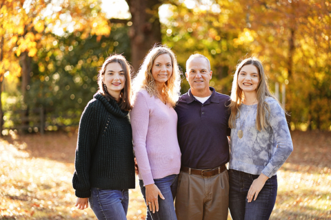 A family of standing with trees behind