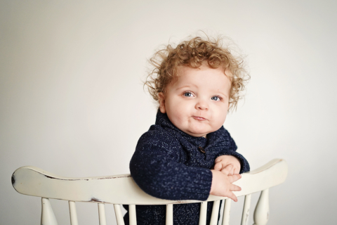 A child wearing blue cloths posing on a white chair