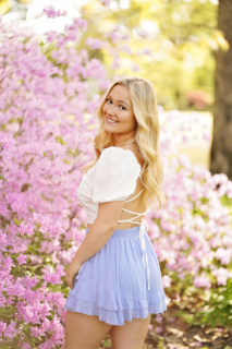 A beautiful girl wearing white and blue in front of flowers