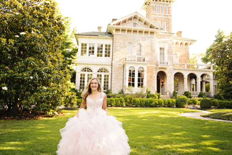 A girl wearing a white dress in front of a house