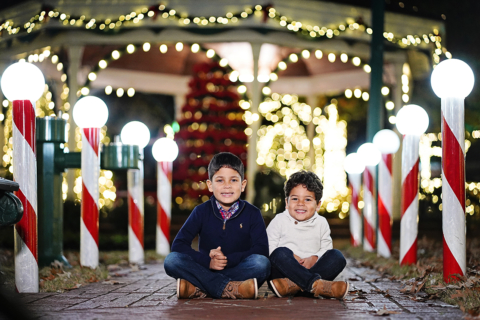 Two childrens sitting on ground with lights all around