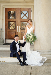 A bride and groom with white flowers in front of a door