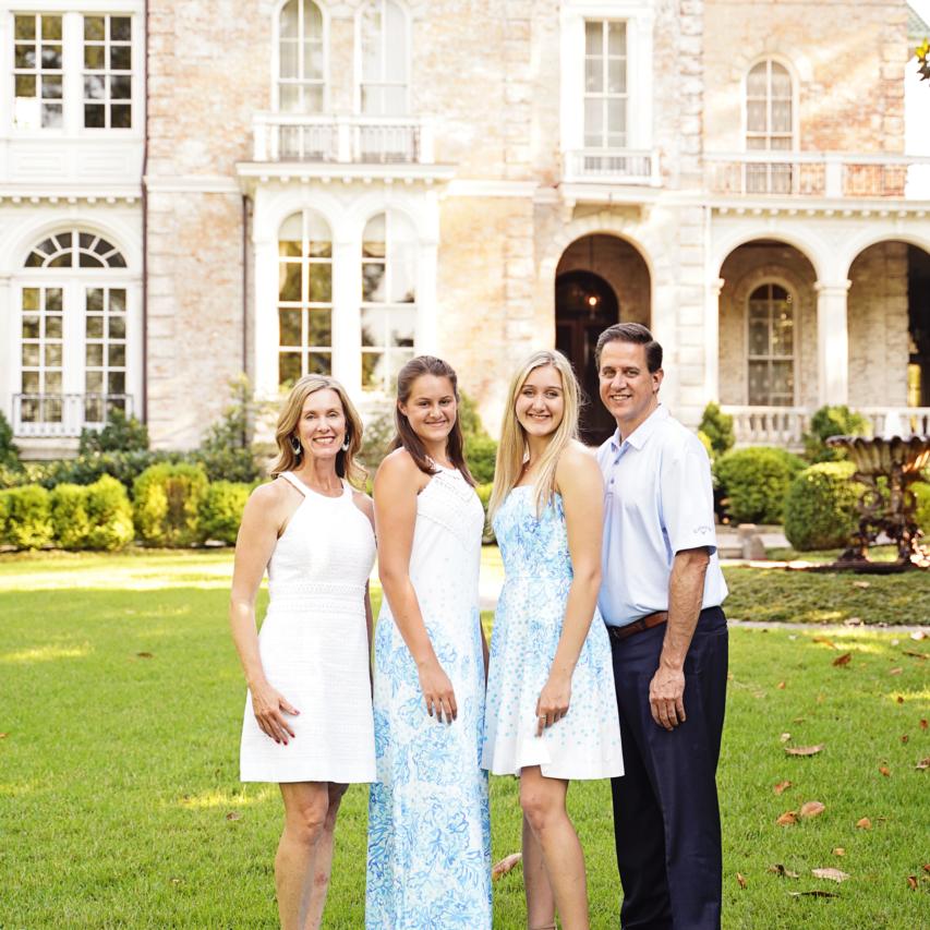 A group of people standing on a lawn in front of a mansion