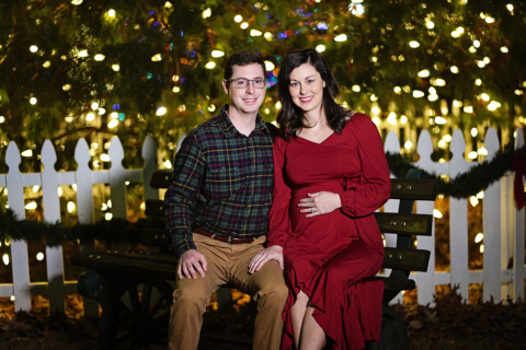 A pregnant woman wearing red dress and sitting with her husband