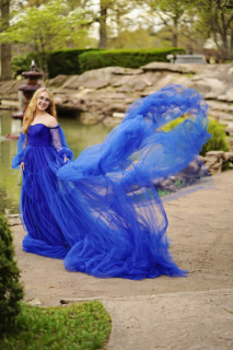 A girl in long blue dress in front of a pond