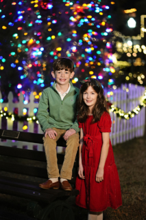 A boy and a girl in front of Christmas lights