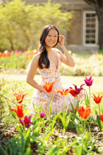 A girl smiling with different flowers in the front