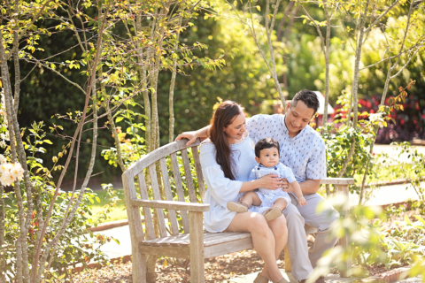 A family of three sitting in a garden bench