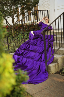 A woman wearing a purple dress and posing on the stairs