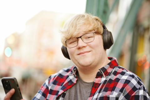 A man wearing headphones and holding a mobile
