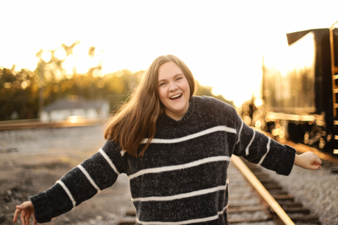 A girl standing on train tracks on a sunny day